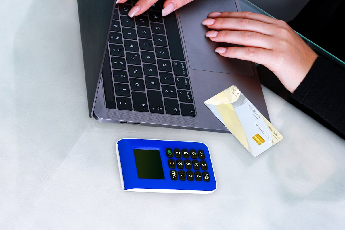 Person typing on laptop with card reader for virtual terminal payment